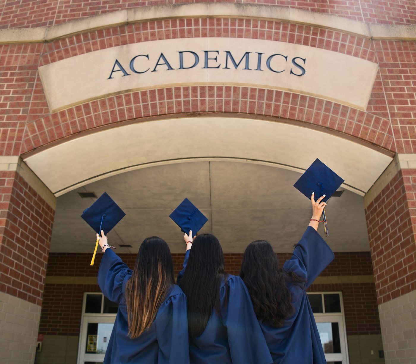Graduates in caps and gowns under an academics archway