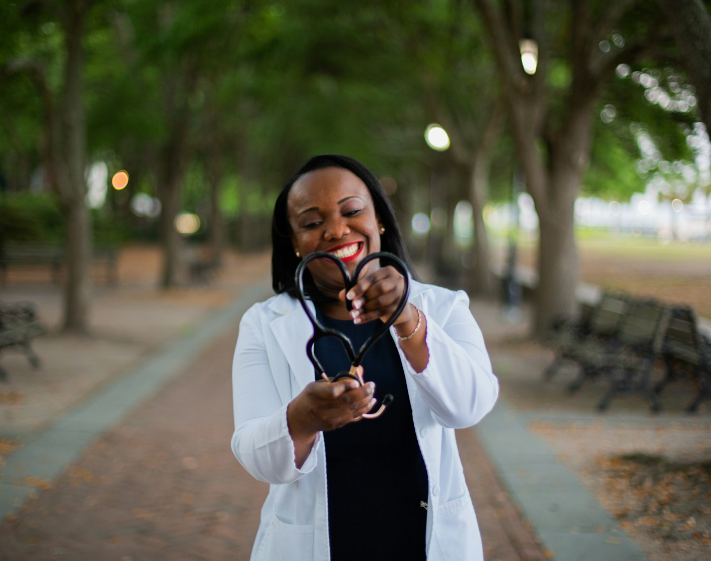 Smiling nurse holding a stethoscope outdoors