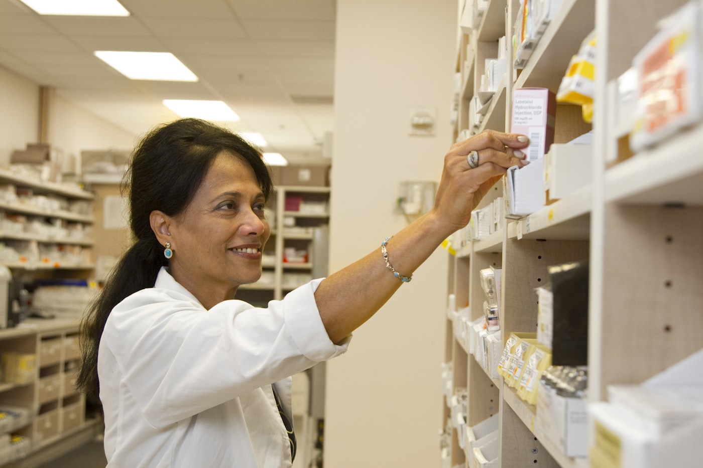 Pharmacist arranging medicines on pharmacy shelves
